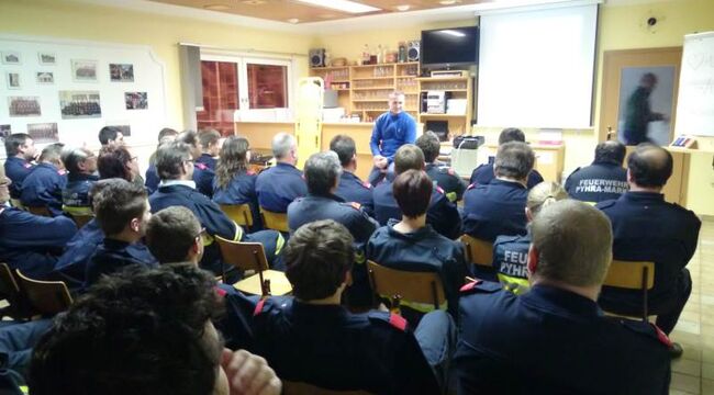 Foto: Etwa 50 Feuerwehrkameraden bei einer theoretischen Ausbildung im Lehrsaal (von hinten fotografiert)