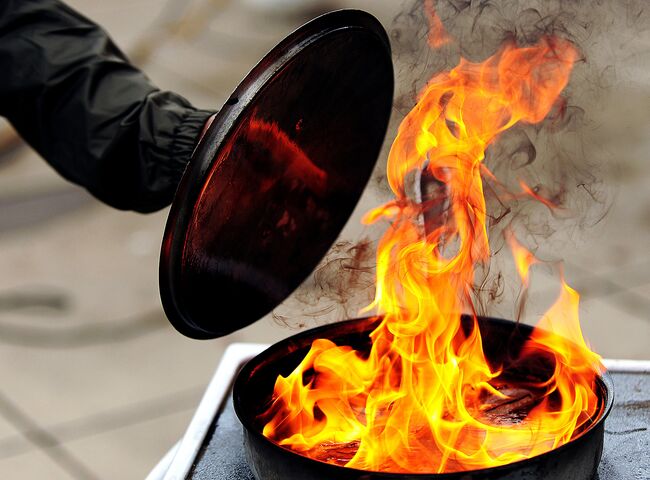 Das Feuer in einer Pfanne wird durch Aufsetzen des Deckels erstickt