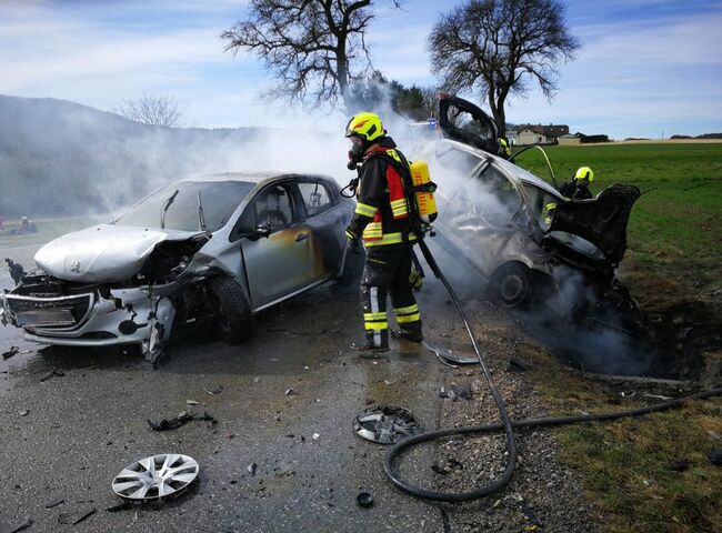 Zwei Feuerwehrmänner mit Atemschutzausrüstung bekämpfen einen KFZ-Brand